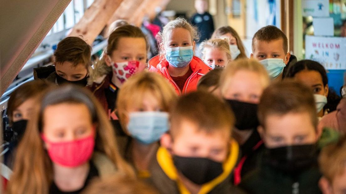 Leerlingen van een basisschool dragen mondkapjes in de gang.