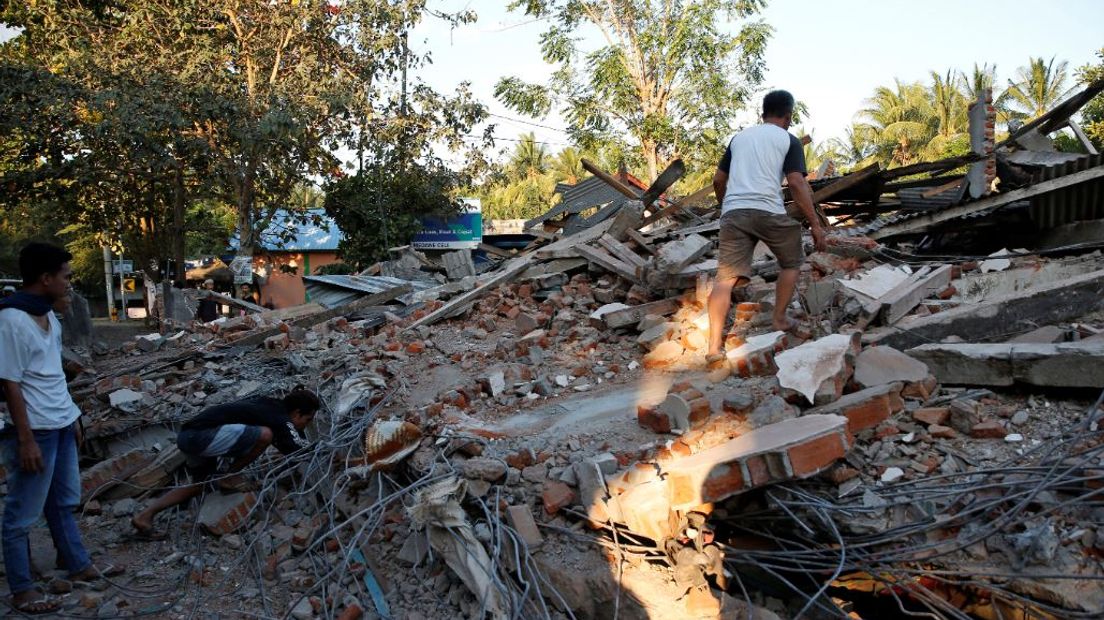 Mannen zoeken in de puinhopen van een ingestort huis naar mogelijke overlevenden.