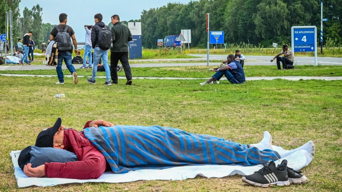 Een asielzoeker ligt op het gras voor het aanmeldcentrum