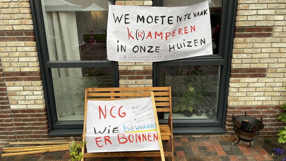 Protestborden met onder meer de tekst: 'We moeten te vaak k(r)amperen in onze huizen