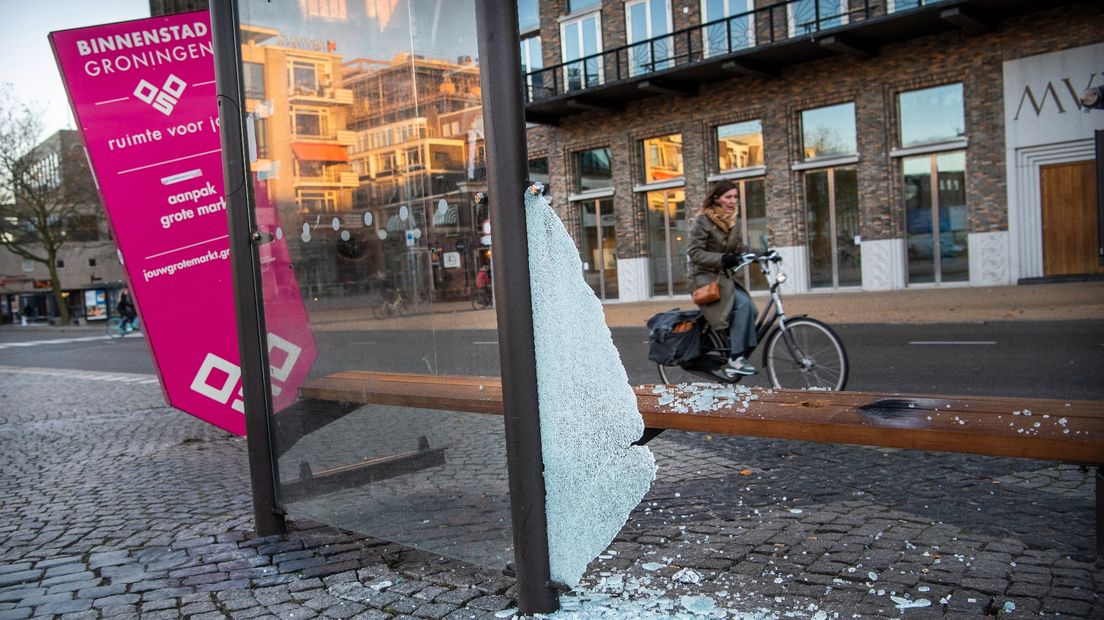 Een vrouw rijdt langs de sporen van de rellen op de Grote Markt in Stad
