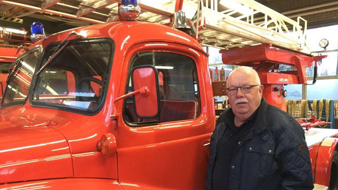 Dick Zwart, poseert naast een oude brandweerwagen.