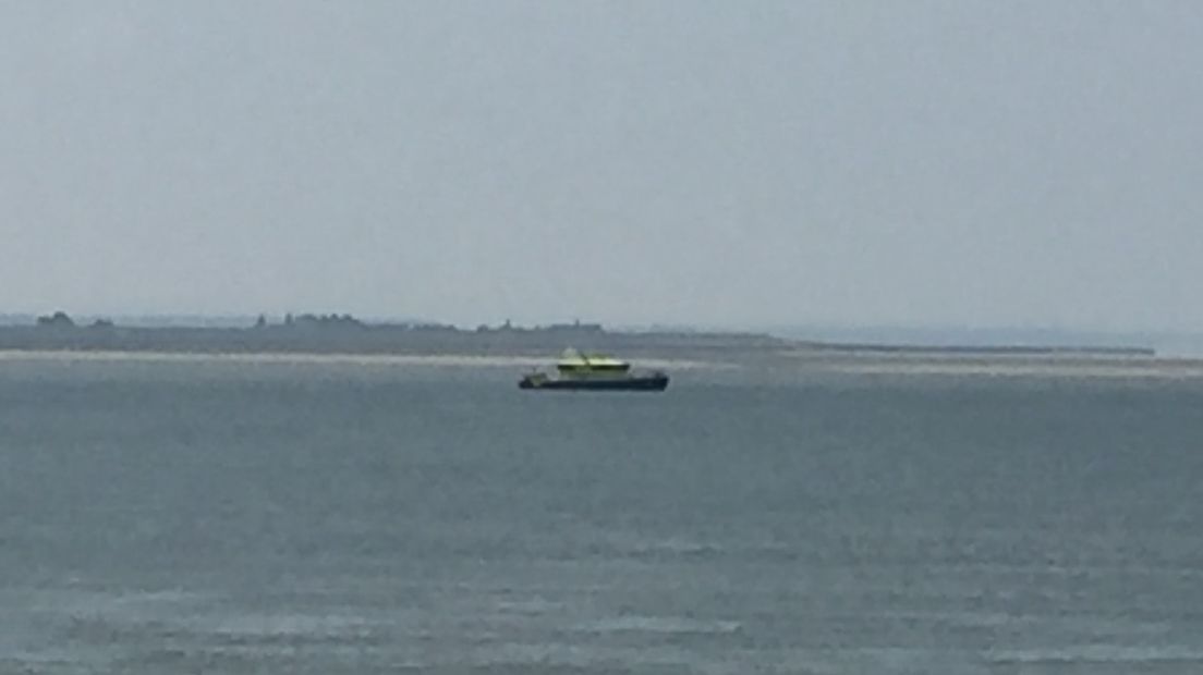 Voor de kust van Hansweert begeleidt een schip van Rijkswaterstaat de scheepvaart