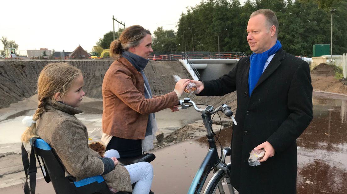 Wethouder Stroobosscher geeft een krentenbol aan een vrouw die door de tunnel fietst.