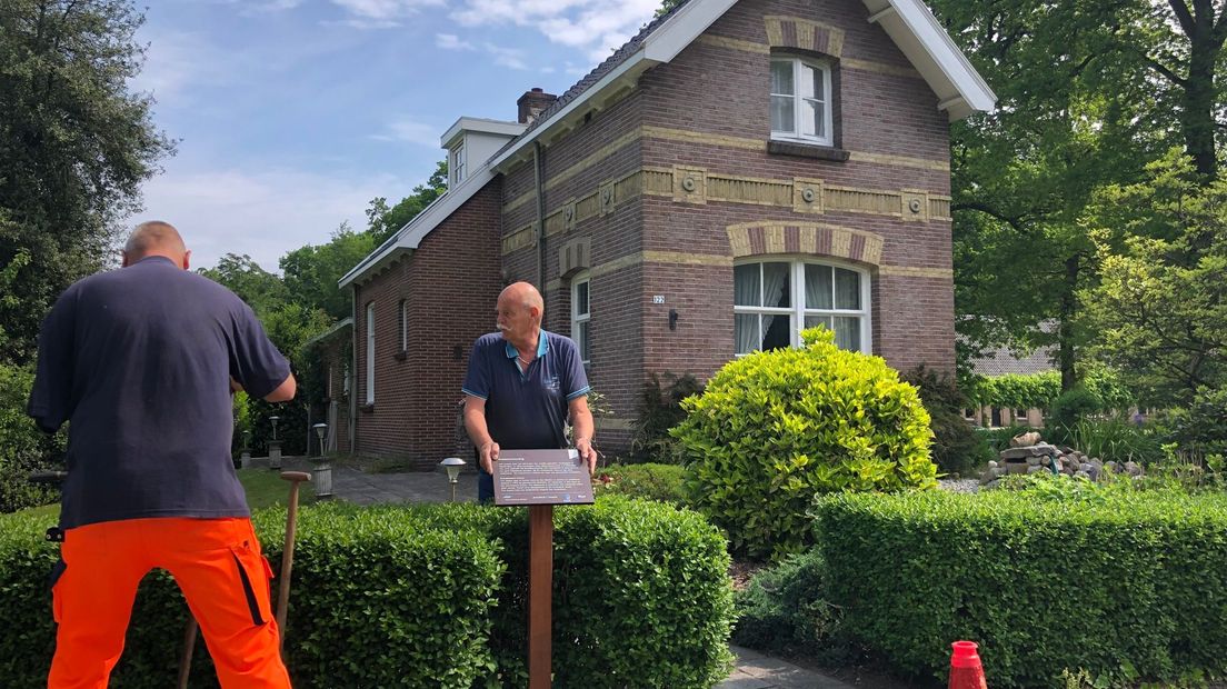 Een nieuw monumentenbord wordt voor de Koetsierswoning in Veenhuizen gezet