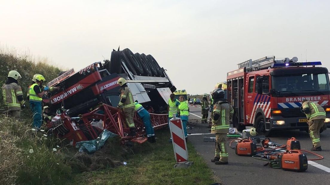De kraanwagen ligt op z'n kop in de berm