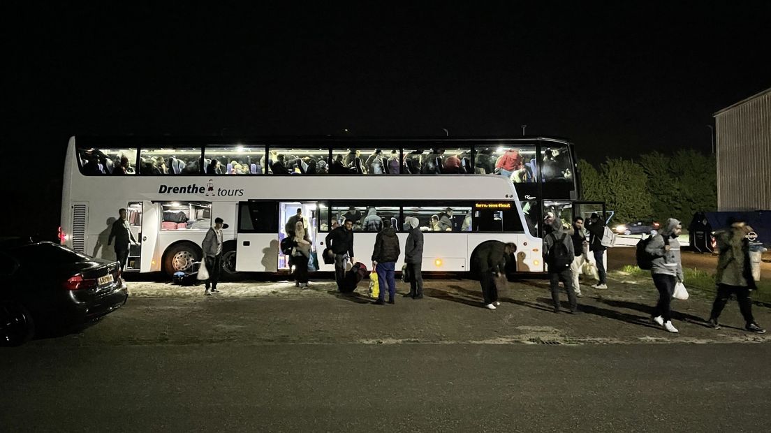 Asielzoekers bij een bus die ze naar een noodopvanglocatie brengt (archief)