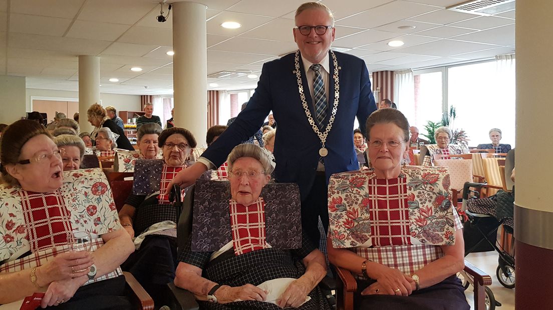 De oudste en jongste klederdracht draagsters poseren met de burgemeester