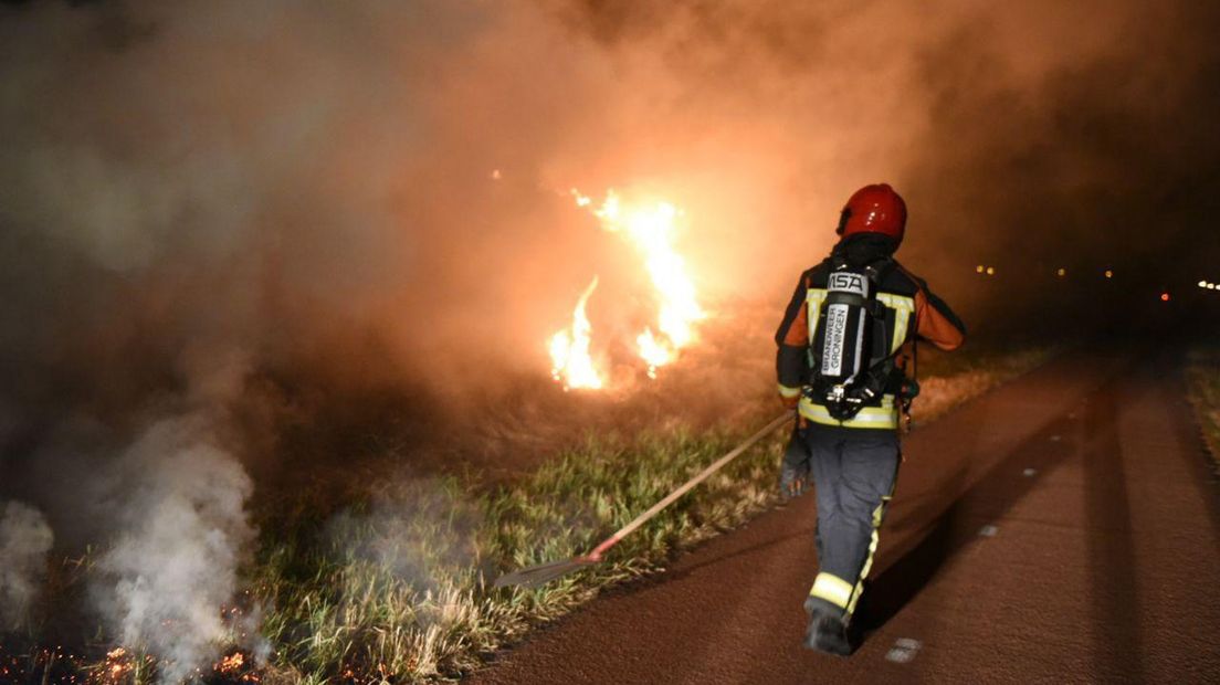 Een brandweerman blust de bermbrand aan de Hoorntjesweg Winschoten.