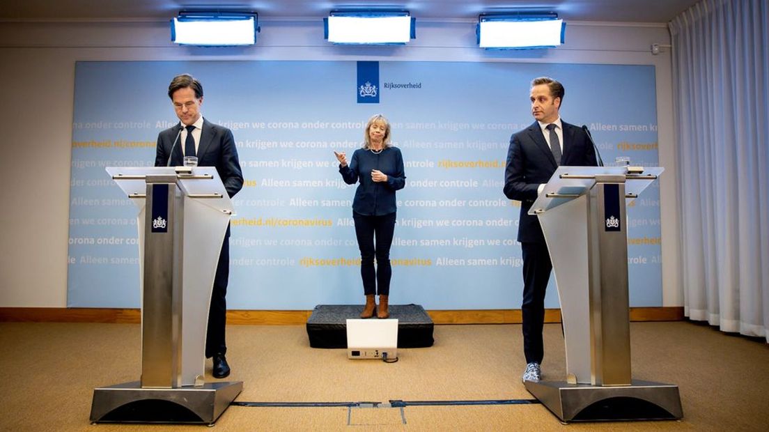 Premier Rutte, minister De Jong en de gebarentolk tijdens een eerdere coronapersconferentie.