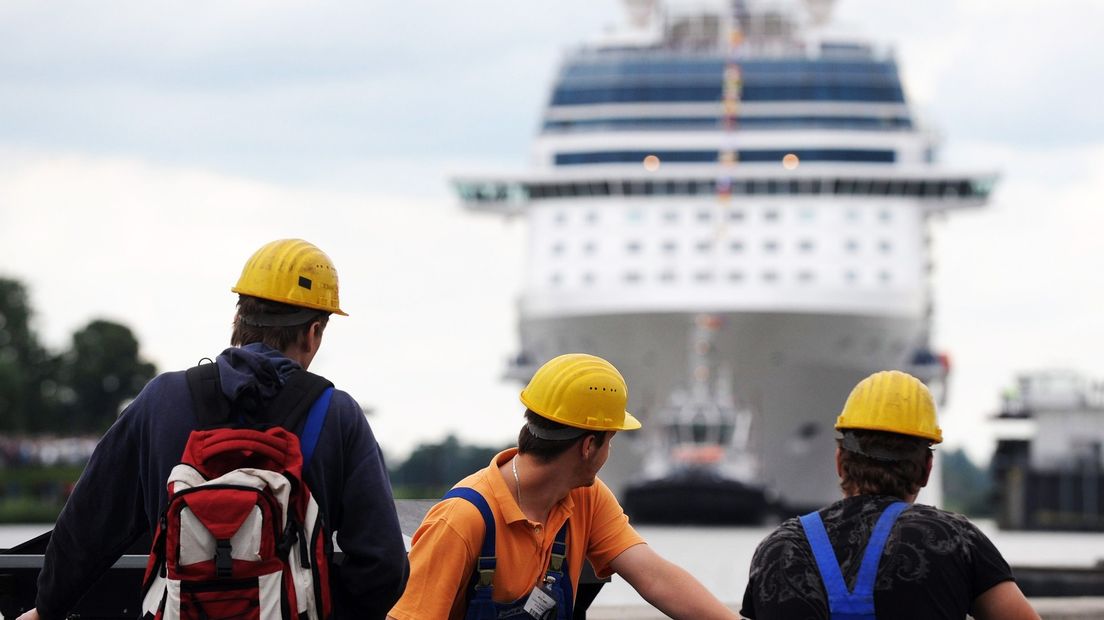 Medewerkers zien een cruiseschip de scheepswerf verlaten