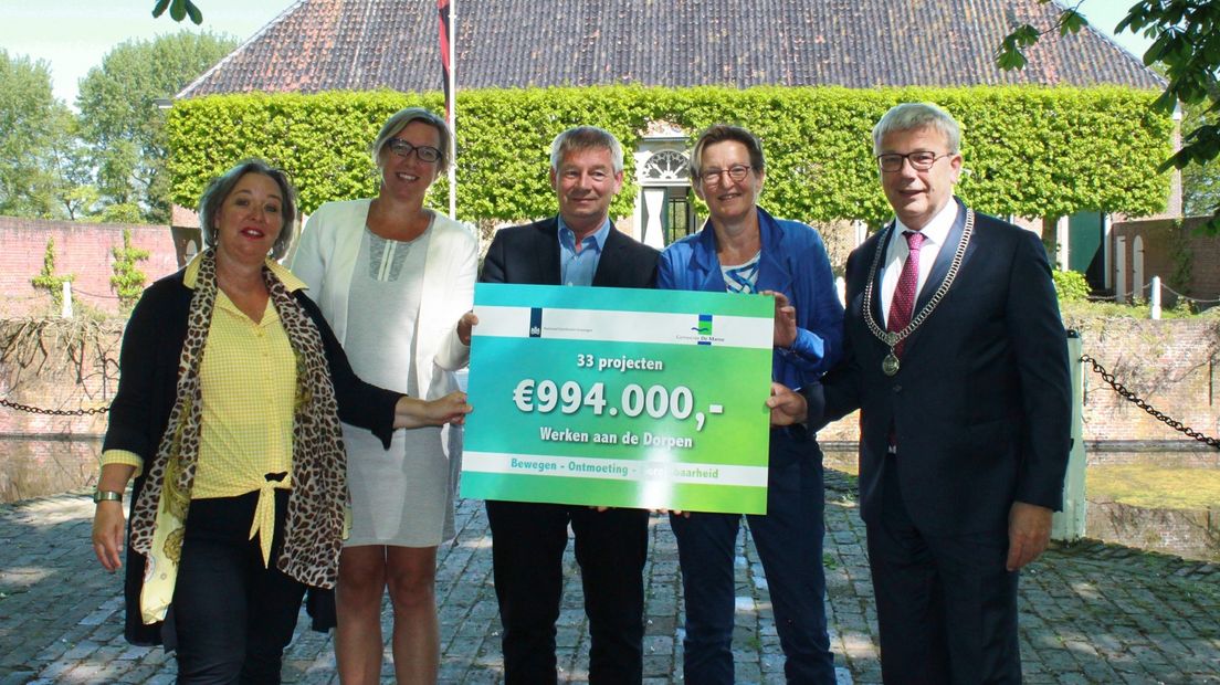 De cheque van bijna een miljoen euro wordt overhandigd