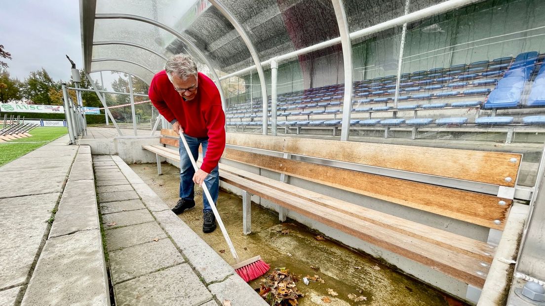 Een vrijwilliger van ACV veegt de dug outs schoon