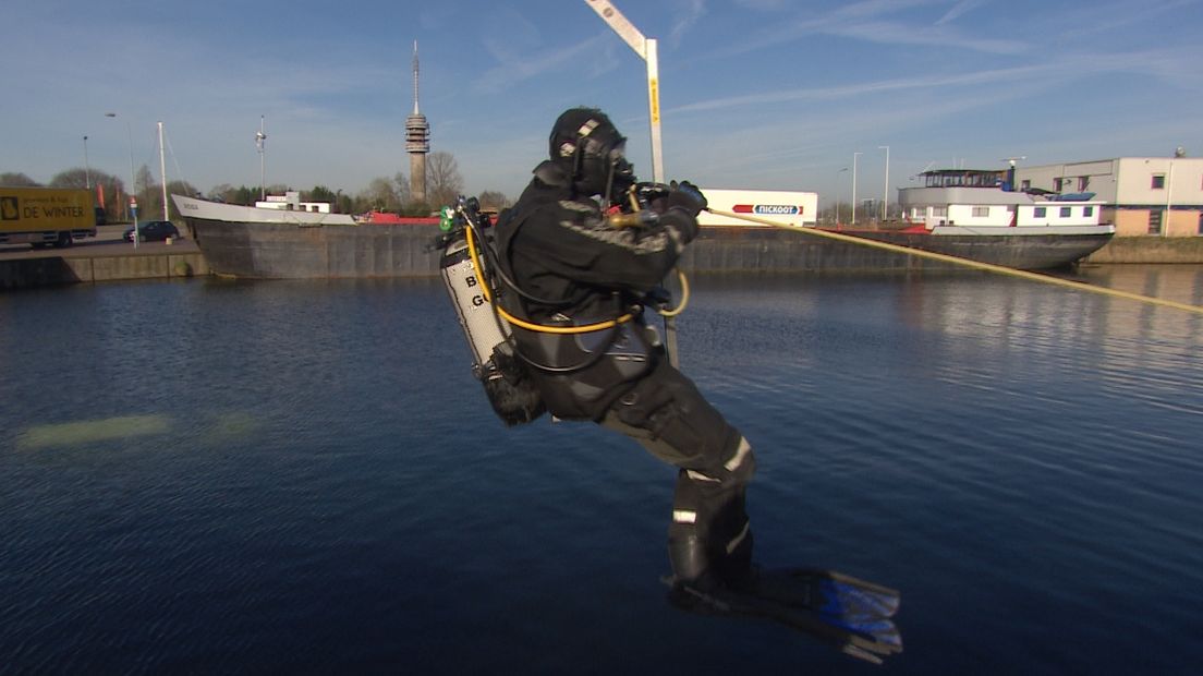 Brandweerduiker wordt het water in getakeld tijdens oefening in de haven van Goes
