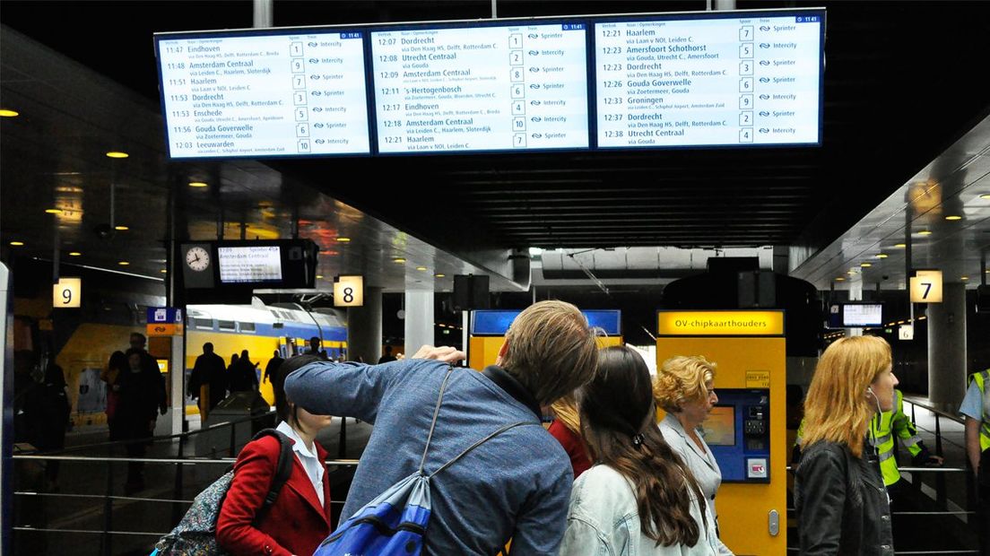 Reizigers kijken op het treinenvertrekbord op Den Haag Centraal
