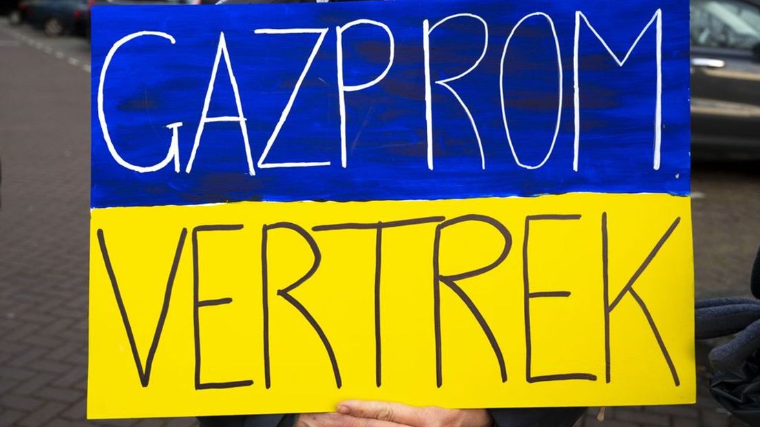 Een demonstrant pleit voor het vertrek van Gazprom vanwege de oorlog in Oekraïne.