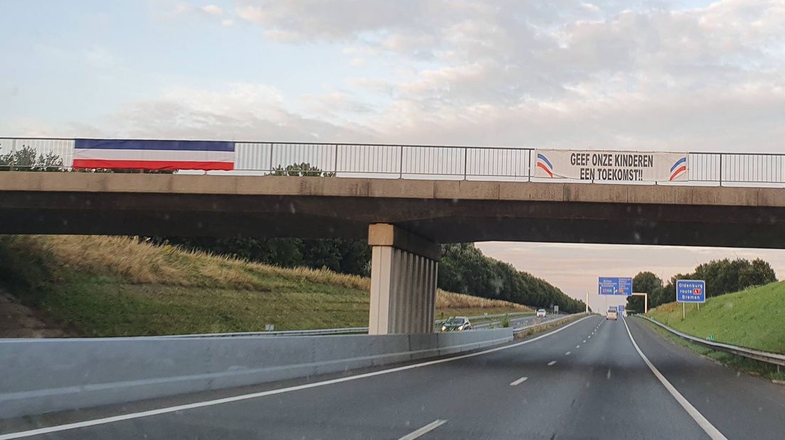 Omgekeerde vlag en spandoek op een viaduct over de A7 bij Zuidbroek