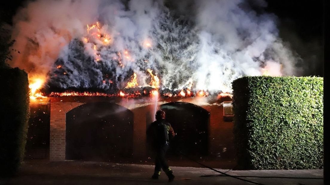 Een brandweerman blust het brandende garagedak