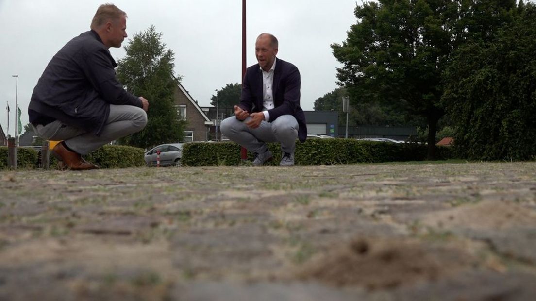 De wespenvriend (links) en burgemeester Rozendaal bekijken de holletjes bij het gemeentehuis