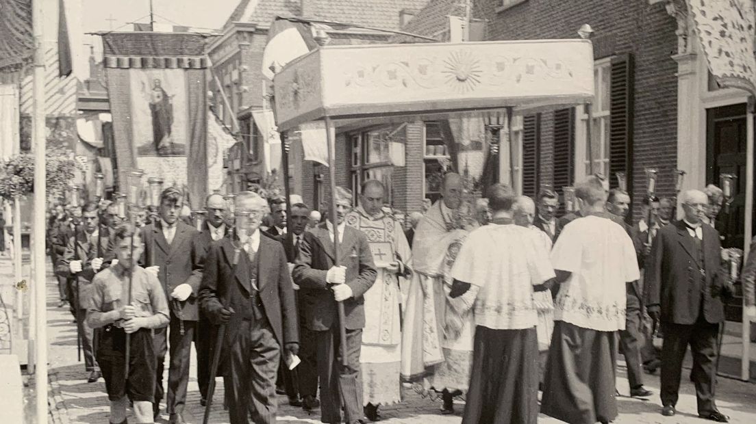 De priester met monstrans onder een baldakijn tijdens een processie