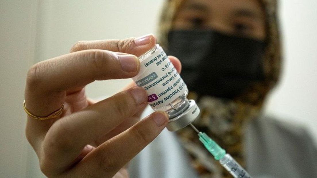 Een zorgverlener is in de weer met het AstraZeneca vaccin.
