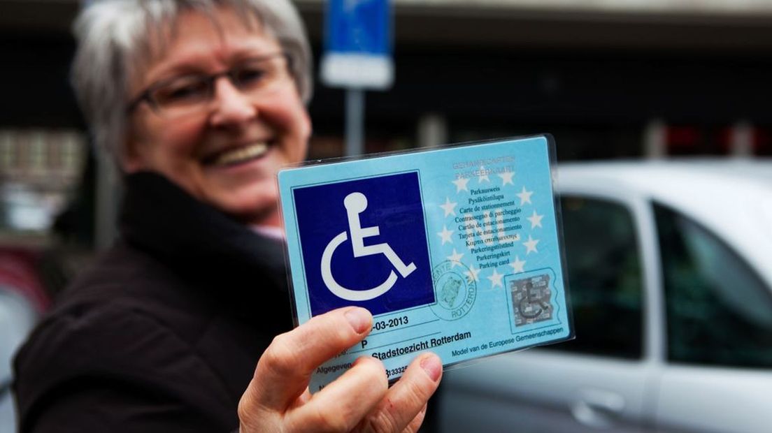 Een vrouw toont haar gehandicaptenparkeerkaart.