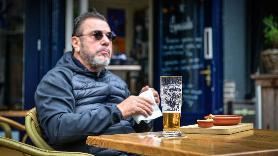 Een man drinkt een biertje op het terras