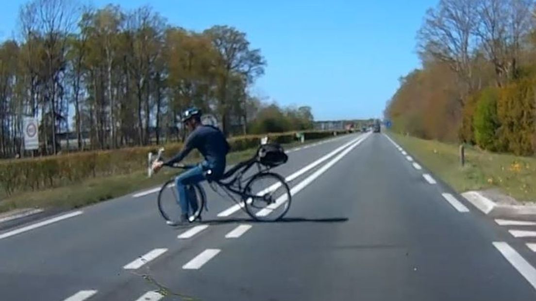 Deze ligfietser peddelt op het laatste moment de weg over.