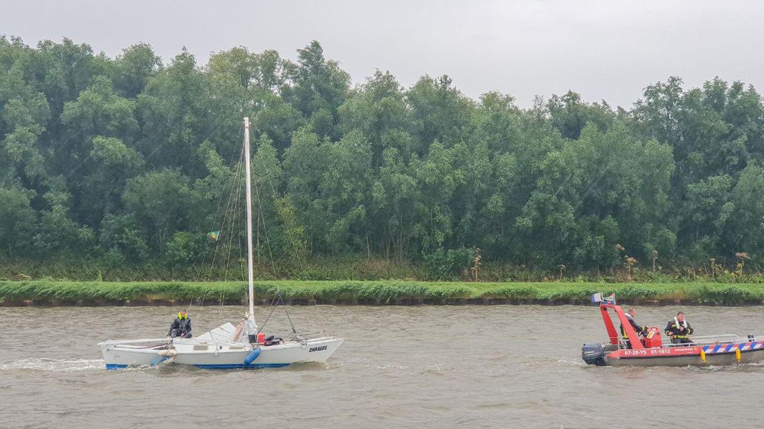 De catamaran die zijn motor verloor, wordt voortgetrokken door een boot van de brandweer.