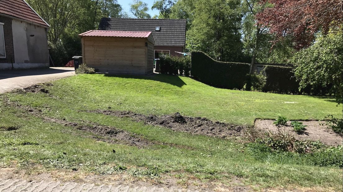 De bandensporen van de auto zijn goed zichtbaar in het gras