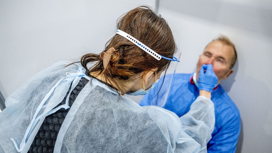 Een GGD-medewerker test een man op corona