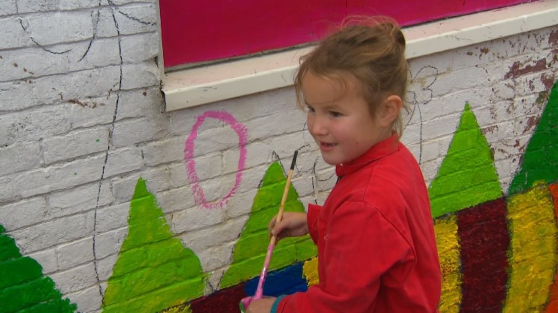 Een van de kinderen schildert een paasei op de woning in Stedum