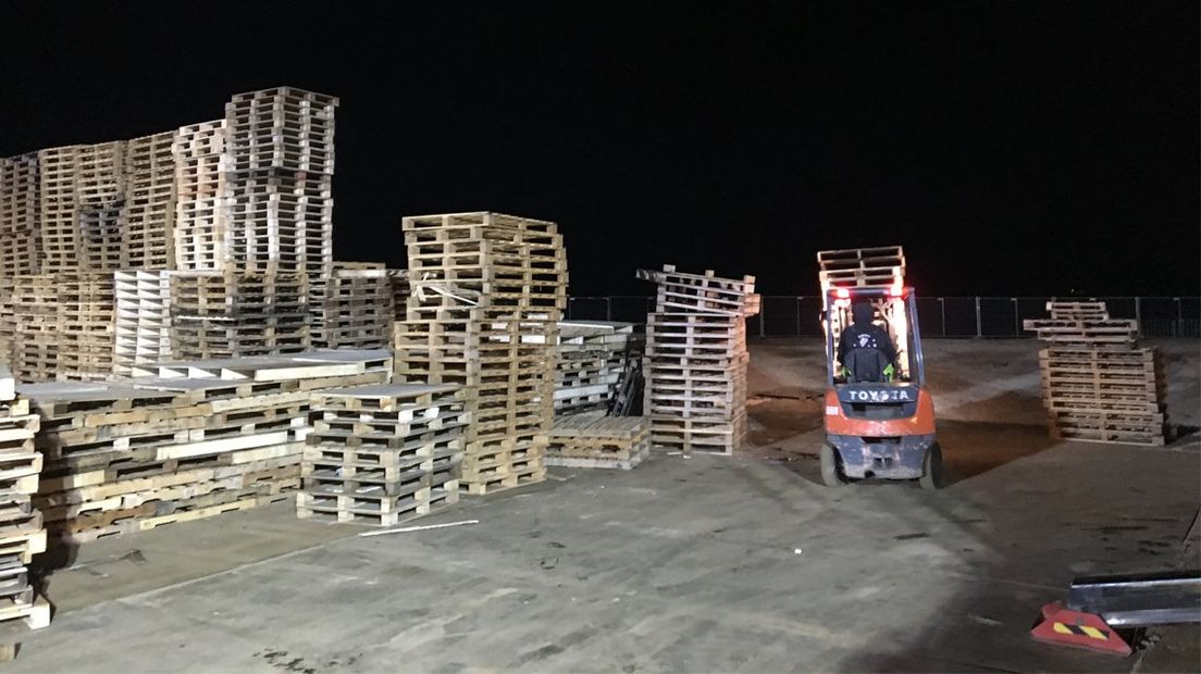 Heftrucks helpen de Scheveningers met het opbouwen van de vuurstapel. 