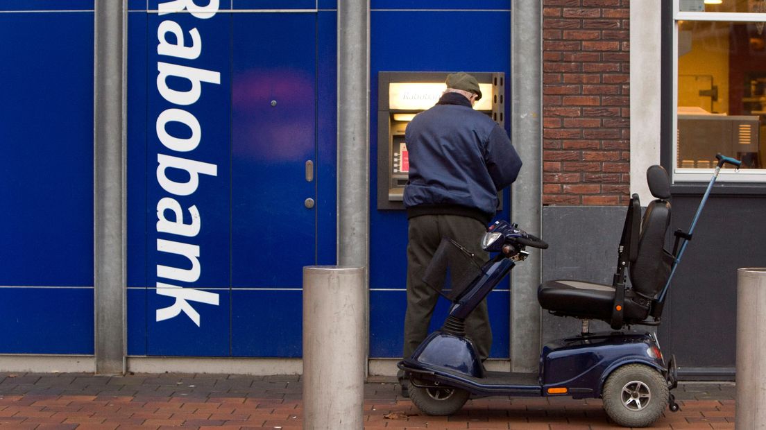 Een man pint bij een automaat van een bankkantoor