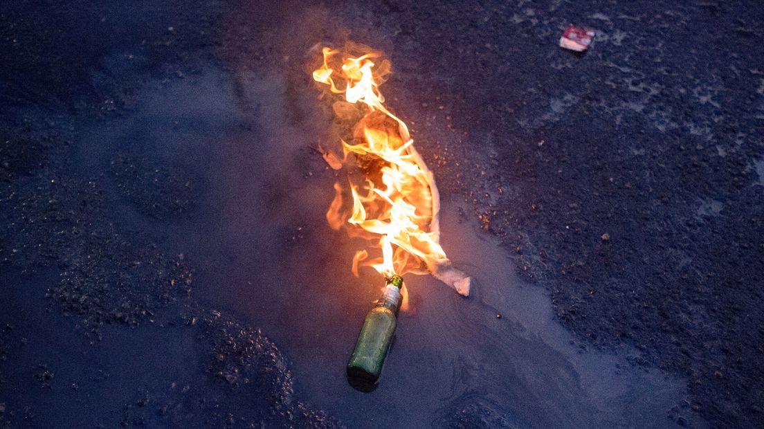 Een brandende molotovcocktail op de grond, ter illustratie