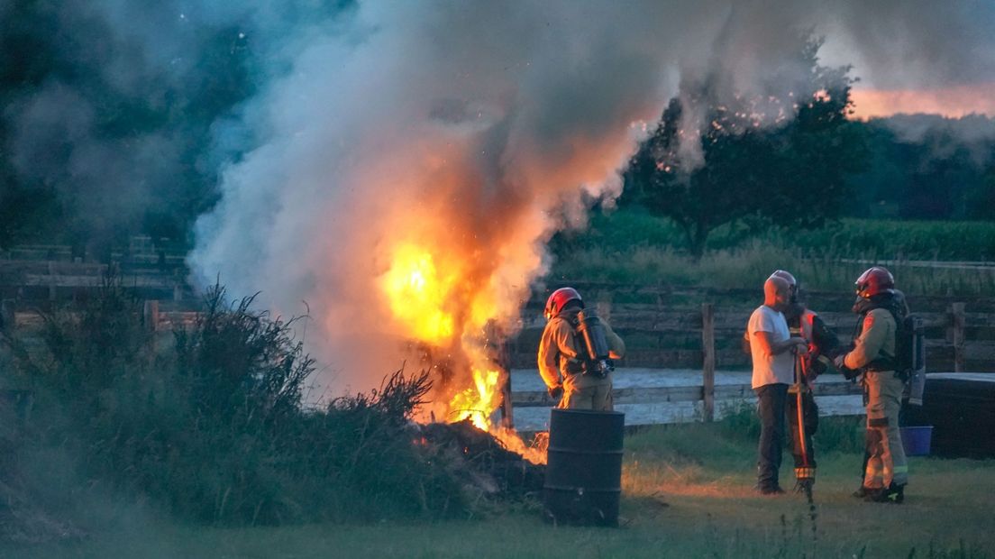 Een brandweerman blust het kampvuur in Midwolda