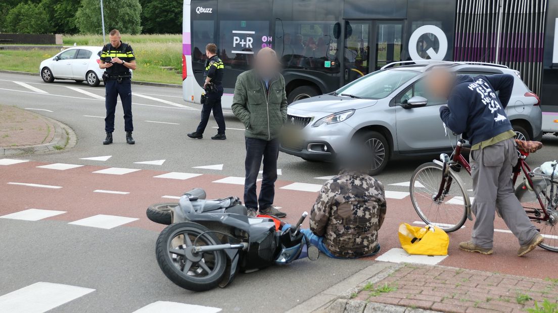 Omstanders ontfermen zich over de aangereden scooterbestuurder