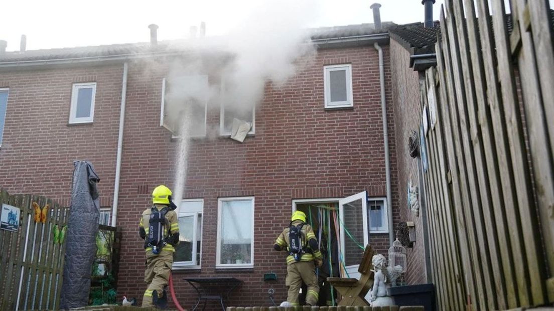 De brandweer bestrijdt het vuur in Herwen van buiten.
