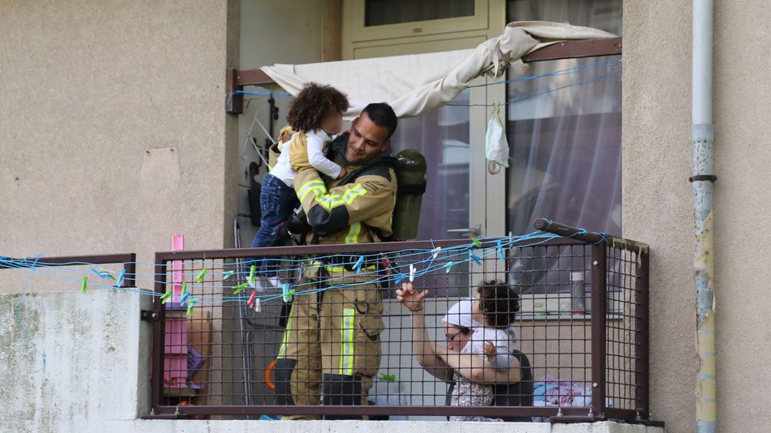 Een brandweerman redt een gezin van het balkon bij een brand.