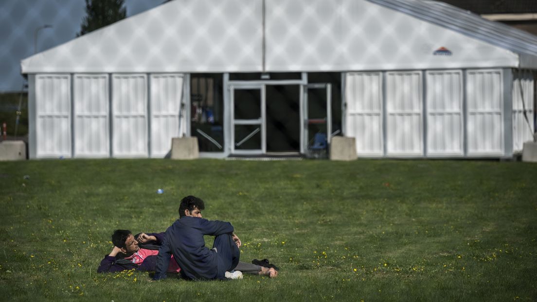 Twee Afghaanse evacués zitten in het gras bij de Willem Lodewijk van Nassaukazerne in Zoutkamp