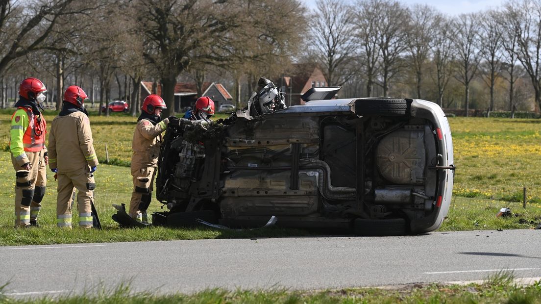 Hulpdiensten bij een auto die op de zijkant is beland na een ongeval