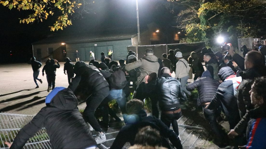 Tegendemonstranten drukken een hek plat om op de Drafbaan te komen
