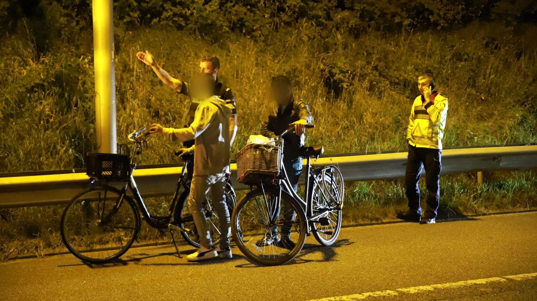 Twee fietsers worden door de politie en Rijkswaterstaat van de snelweg begeleid