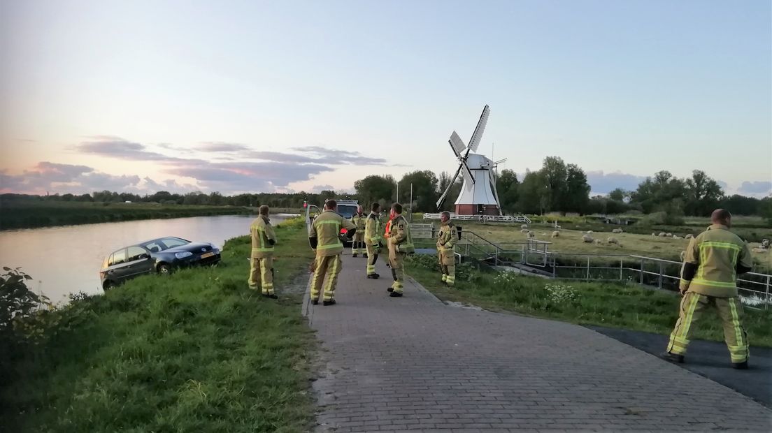 Brandweerlieden zorgen ervoor dat de auto van het slachtoffer weer op de kant getakeld wordt