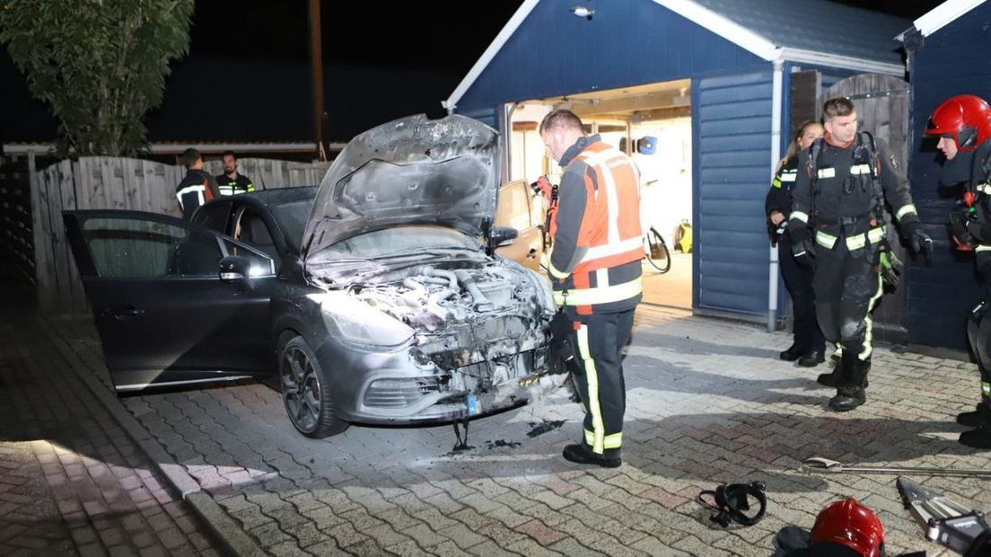 De brandweer bij de auto na de brand