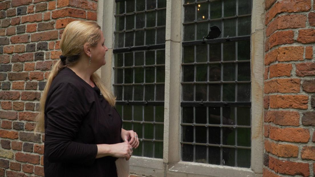 Museumdirecteur Margriet van Klinken inspecteert een beschadigd raam