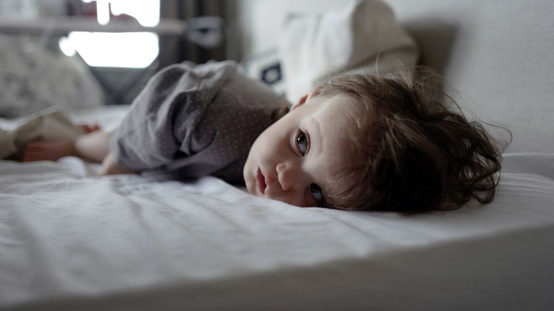 Een kind ligt ziek op bed