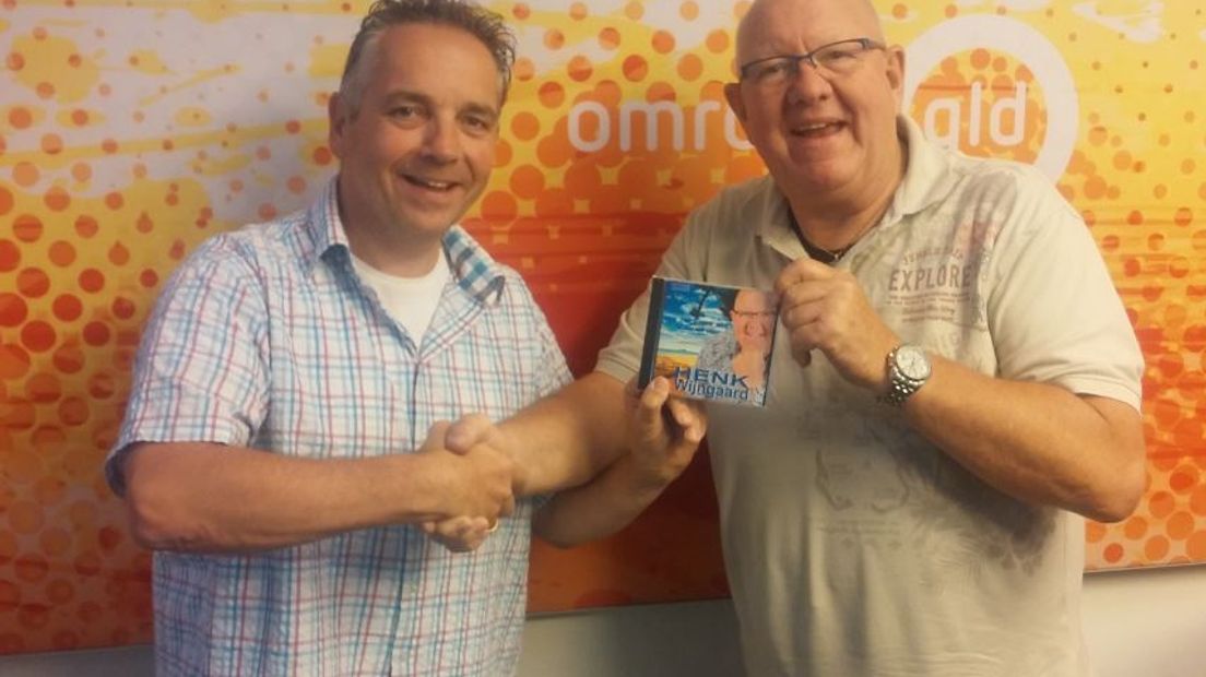 Wijngaard neemt de cd in ontvangst uit handen van Daan Hartgers van Radio Gelderland.