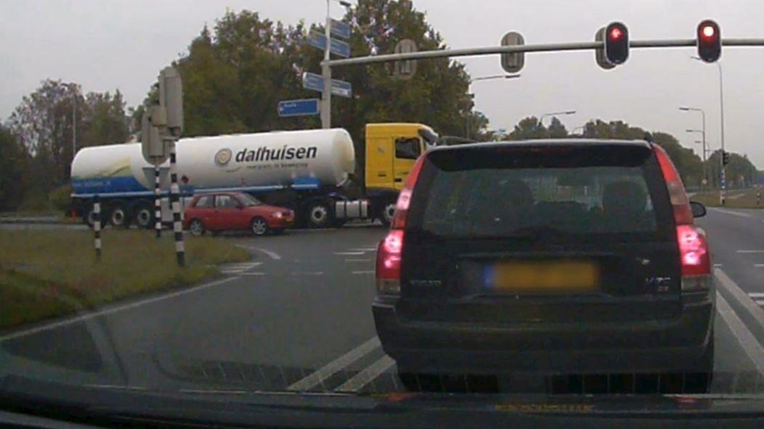 De bestuurder van het rode autootje haalt op doldwaze wijze een traag optrekkende vrachtwagen in