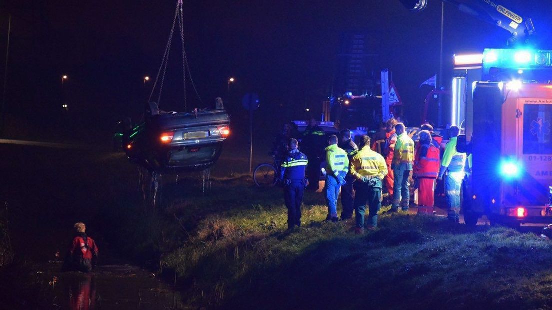De auto wordt door hulpdiensten uit het water getakeld